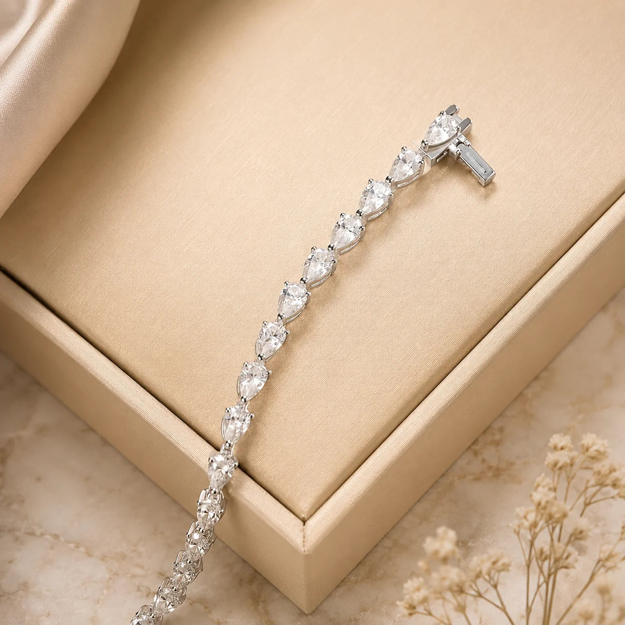 Langley™ pear-cut moissanite tennis bracelet for women displayed elegantly across a champagne jewelry box.
