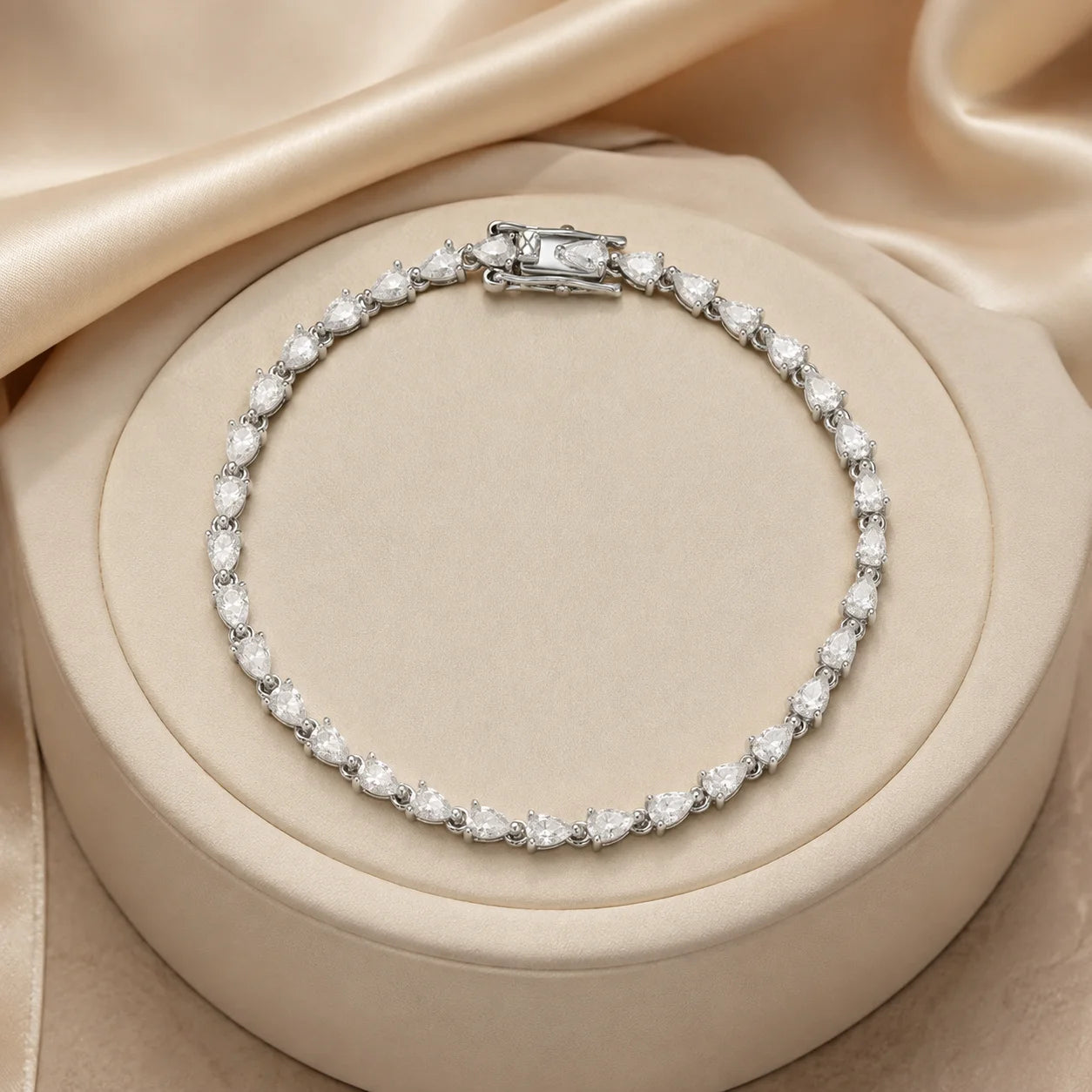 Langley™ pear-cut moissanite tennis bracelet for women displayed on a soft round beige jewelry stand.