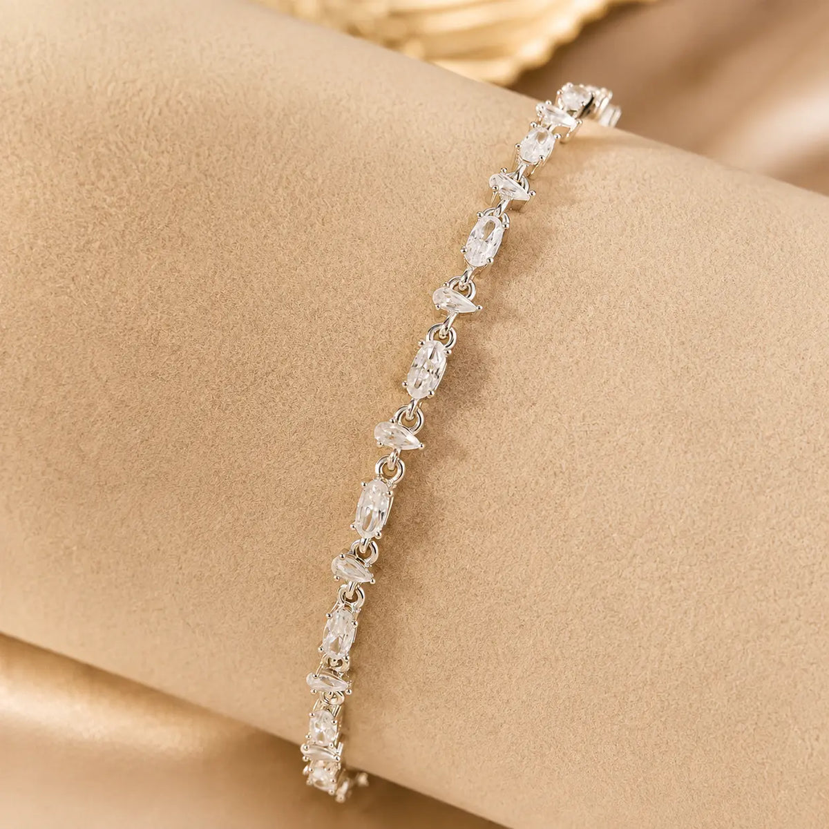 Woman wearing a sparkling mixed-cut moissanite tennis bracelet on her wrist in an elegant beige setting.