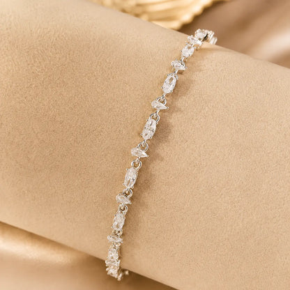 Woman wearing a sparkling mixed-cut moissanite tennis bracelet on her wrist in an elegant beige setting.