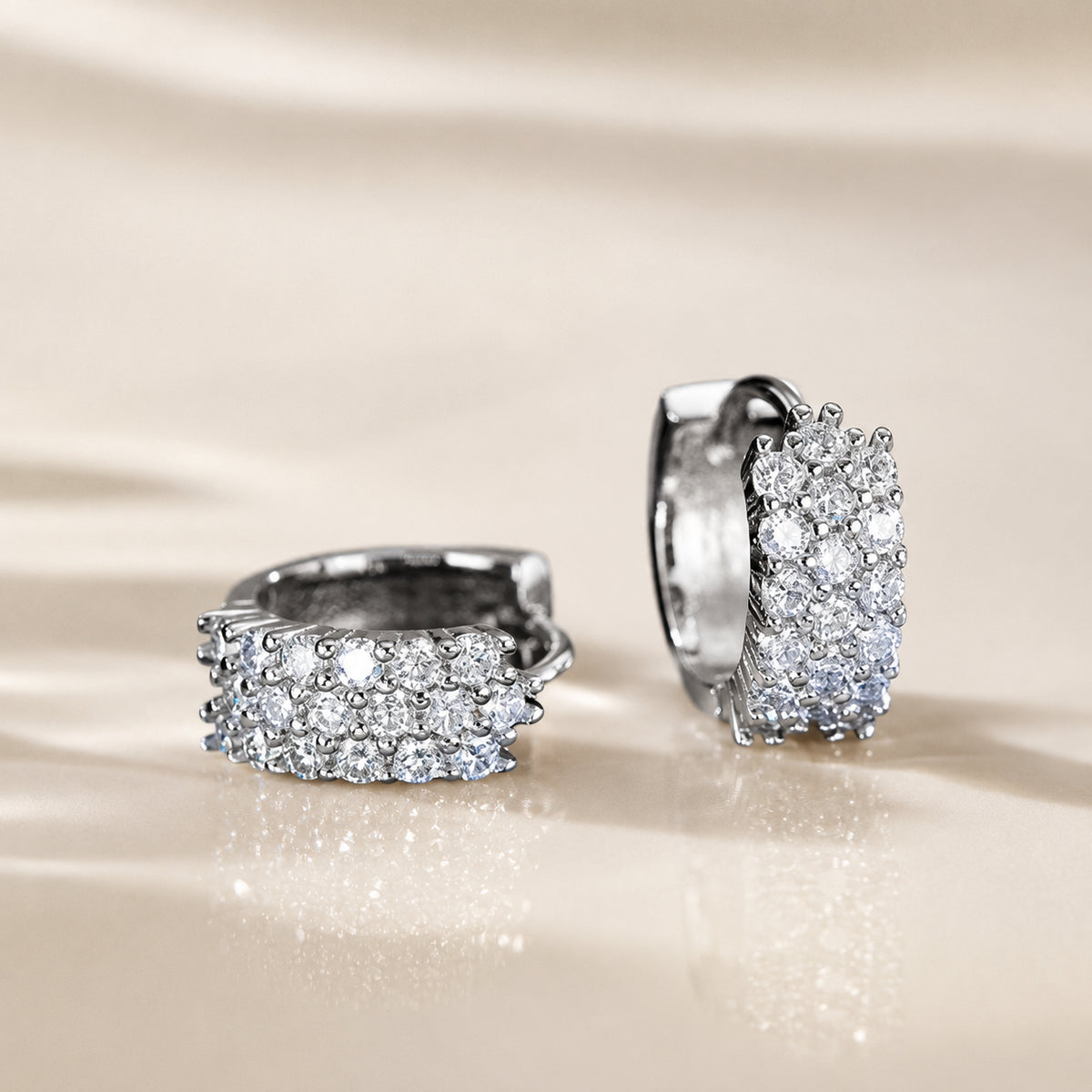 Moissanite hoop earrings displayed on a soft beige background with elegant sparkle and premium silver finish.