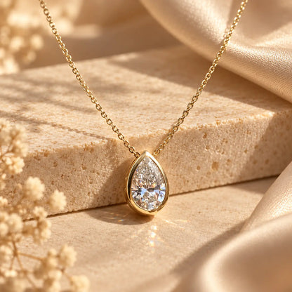 Close-up of a pear cut moissanite solitaire necklace with a delicate gold tone chain