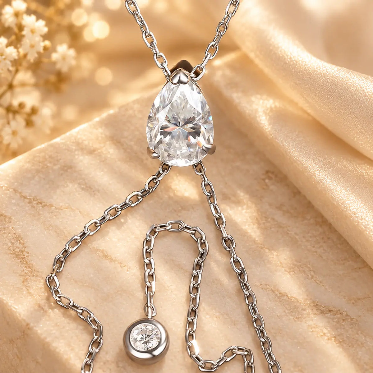 Close-up of a pear cut moissanite Y necklace with two delicate drop chains