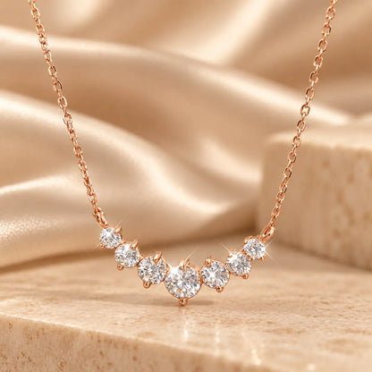 Rose gold tone graduated moissanite necklace with a brilliant center stone