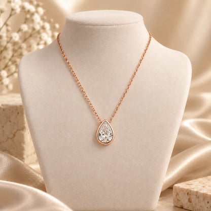 Rose gold tone pear moissanite pendant necklace styled on an elegant beige bust