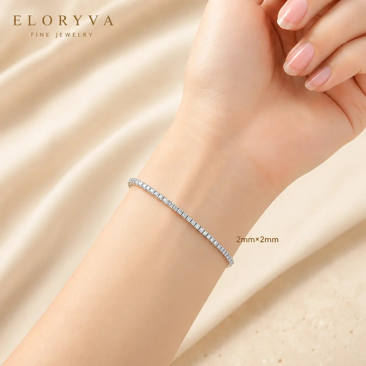 Woman wearing a delicate 2mm round moissanite tennis bracelet on the wrist in an elegant beige setting.