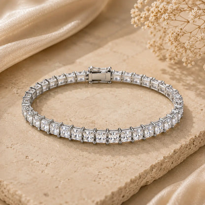 Round moissanite tennis bracelet for women displayed on a beige stone surface with brilliant prong-set stones.