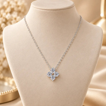 Silver tone clover pendant necklace displayed on a soft beige jewelry stand