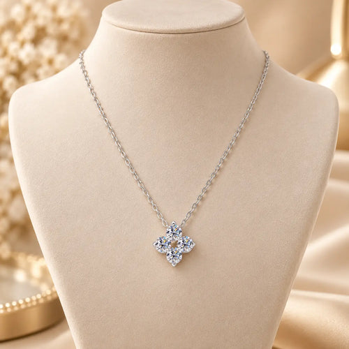 Silver tone clover pendant necklace displayed on a soft beige jewelry stand