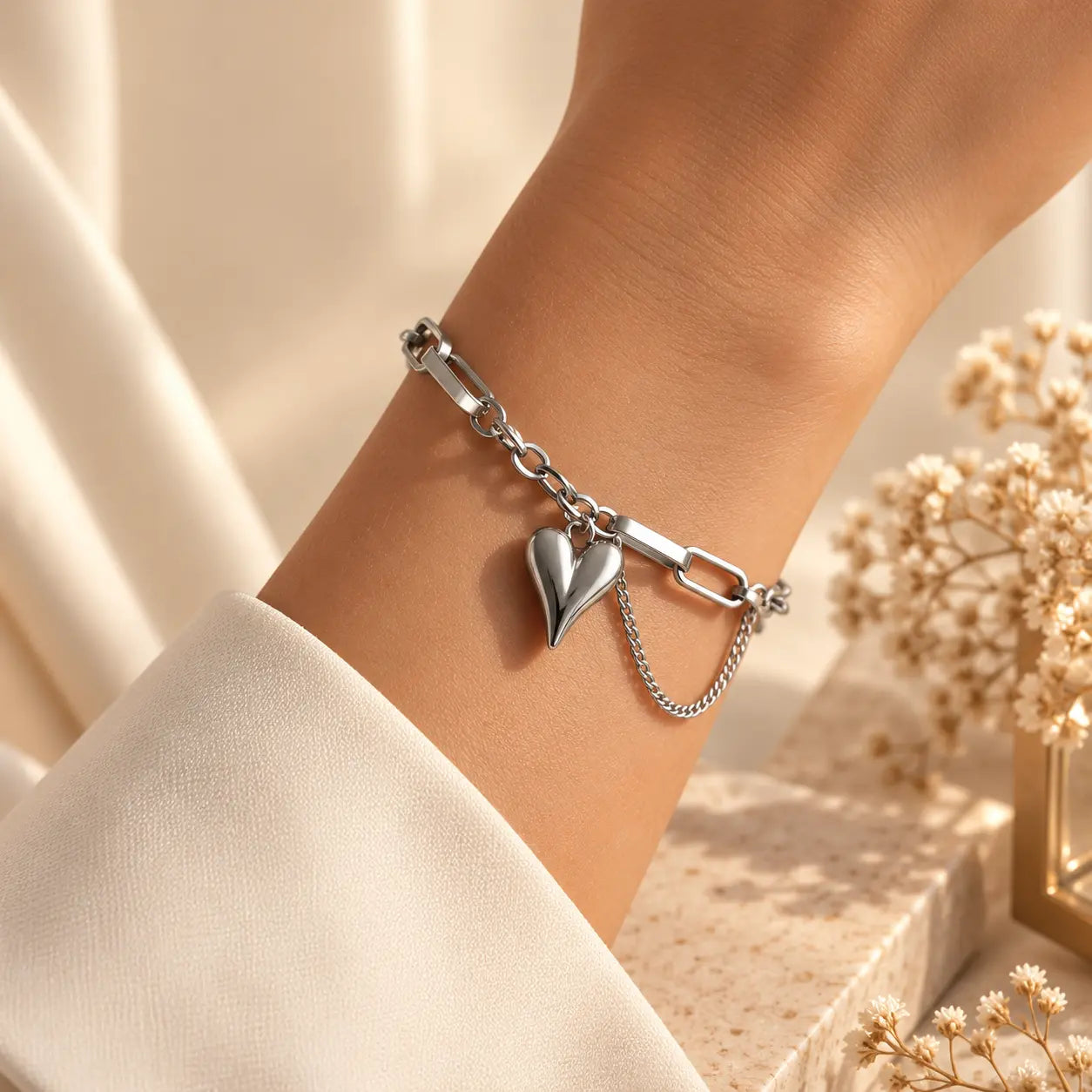 Woman wearing a silver tone heart charm bracelet with delicate chain details