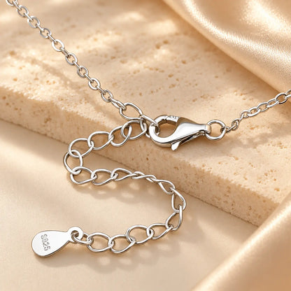 Hand holding a silver tone moissanite Y necklace showing the delicate stone-set drop