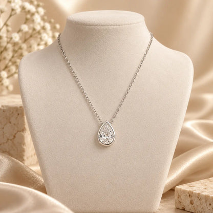 Silver tone pear cut moissanite pendant necklace displayed on a soft beige jewelry bust