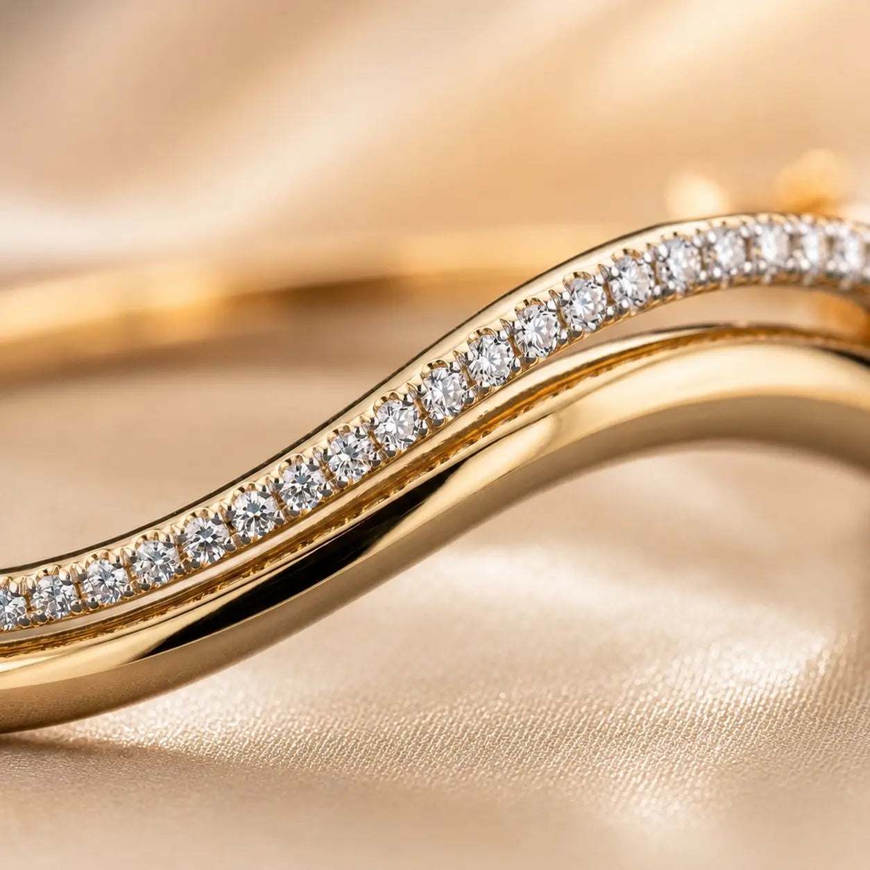 Close-up of a wave moissanite bangle bracelet showing the sparkling stone setting and polished gold-tone curves.